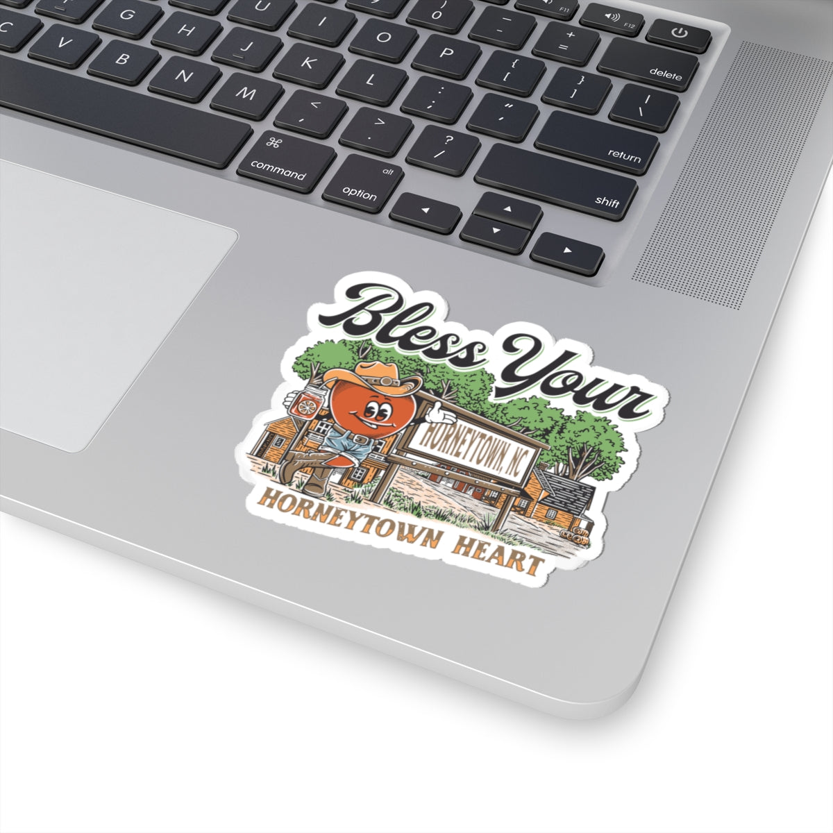 Alt text: "Bless Your Horneytown Heart Sticker - Kiss-Cut Vinyl, featuring a humorous North Carolina-inspired design. The 2" × 2" sticker showcases playful typography with a nod to the small town of Horneytown, NC, set against a backdrop of nature-inspired elements like pine trees and rolling hills, perfect for adding a touch of Southern charm and wit to your belongings."