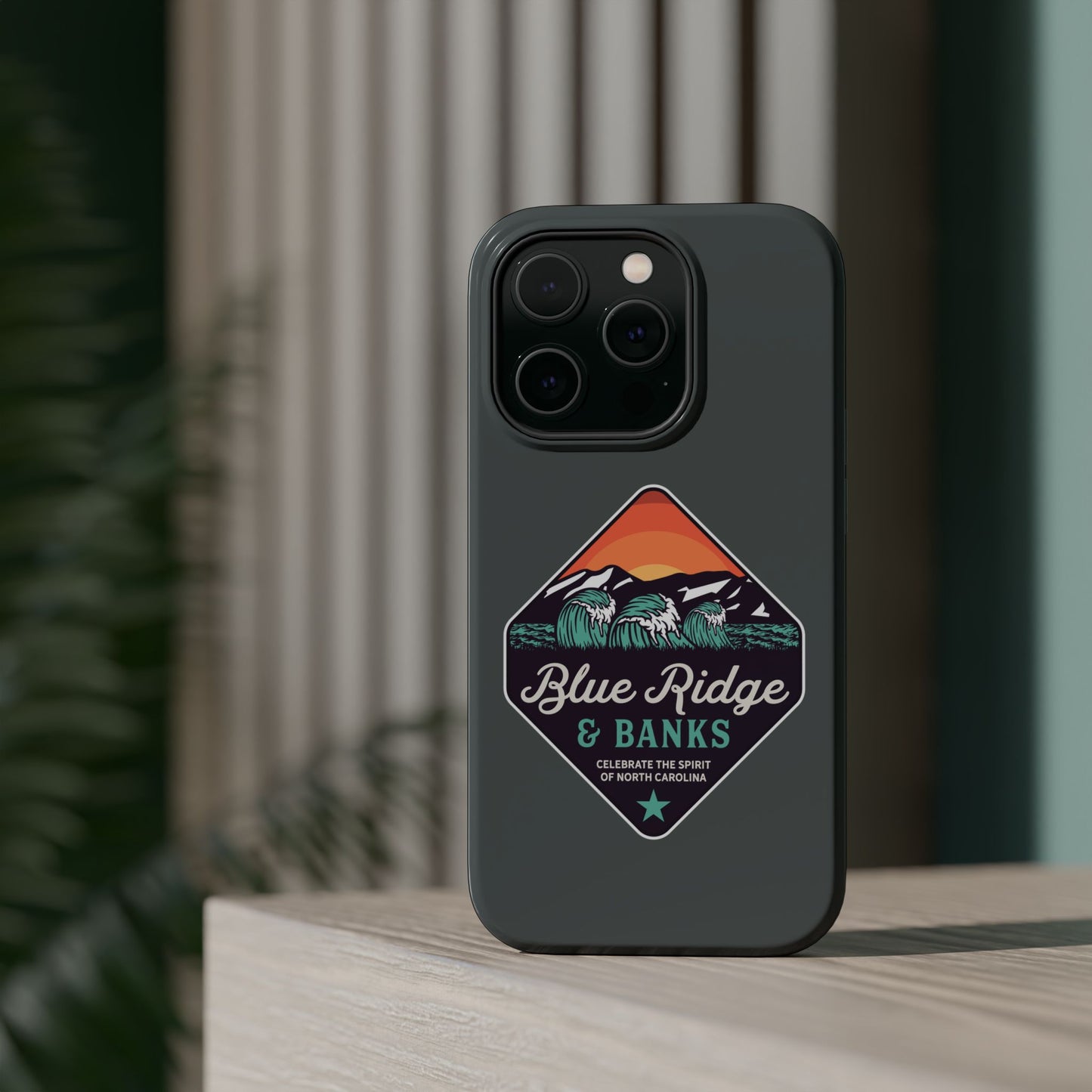"Blue Ridge & Banks Magnetic Tough Case for iPhone 16 - Showcasing a nature-inspired design with North Carolina's Blue Ridge Mountains motif, this case combines rugged protection with artistic flair. Perfect for nature enthusiasts, the case features a durable build and magnetic compatibility, ensuring your device stays safe while reflecting your love for the great outdoors."