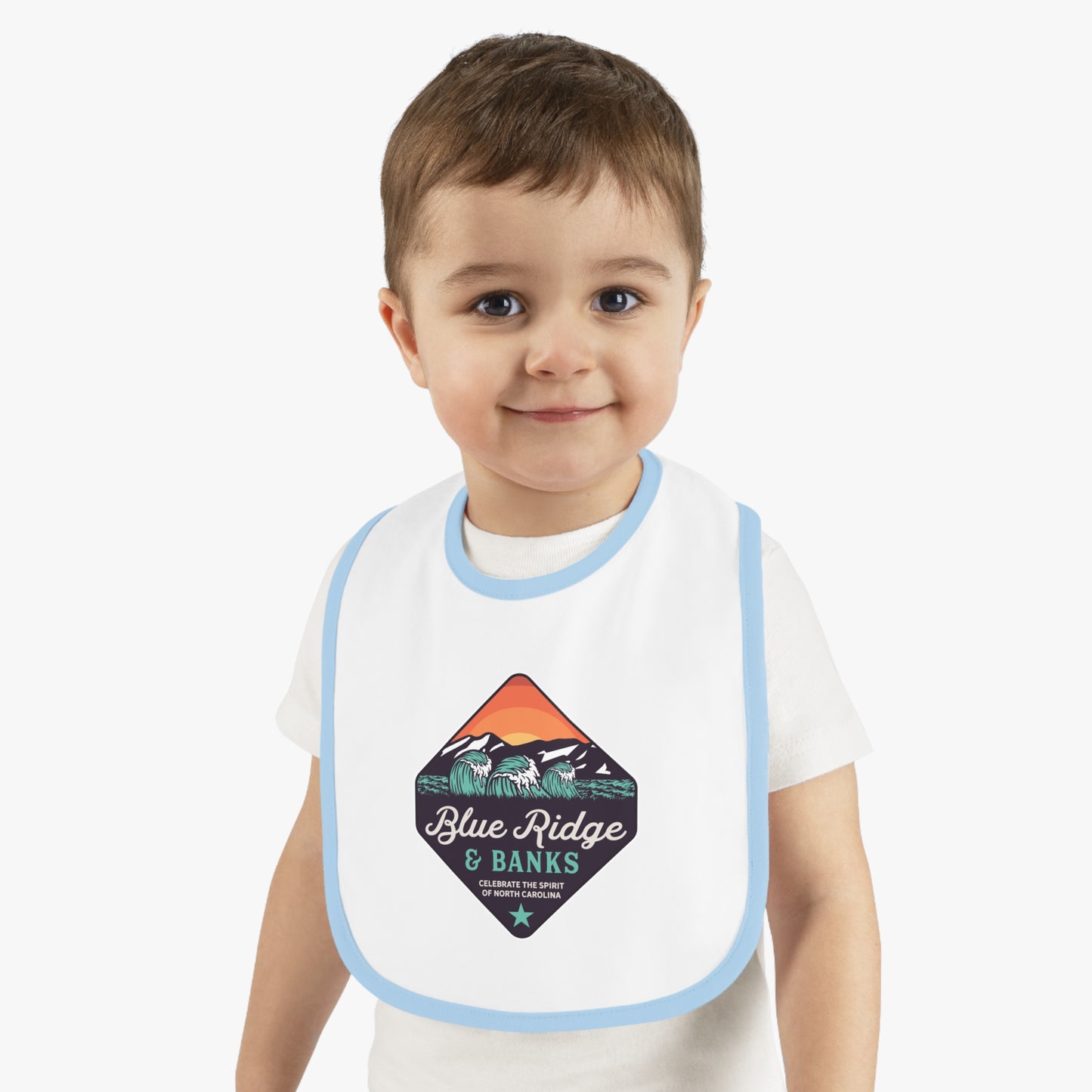 "Blue Ridge & Banks Logo Baby Bib Shirt in White/Light Blue ā Featuring a charming blend of North Carolina's natural beauty, this baby bib shirt showcases a delicate design inspired by the Blue Ridge Mountains and serene riverbanks. The soft white fabric is accented with light blue trims, making it a perfect and stylish choice for nature-loving families."
