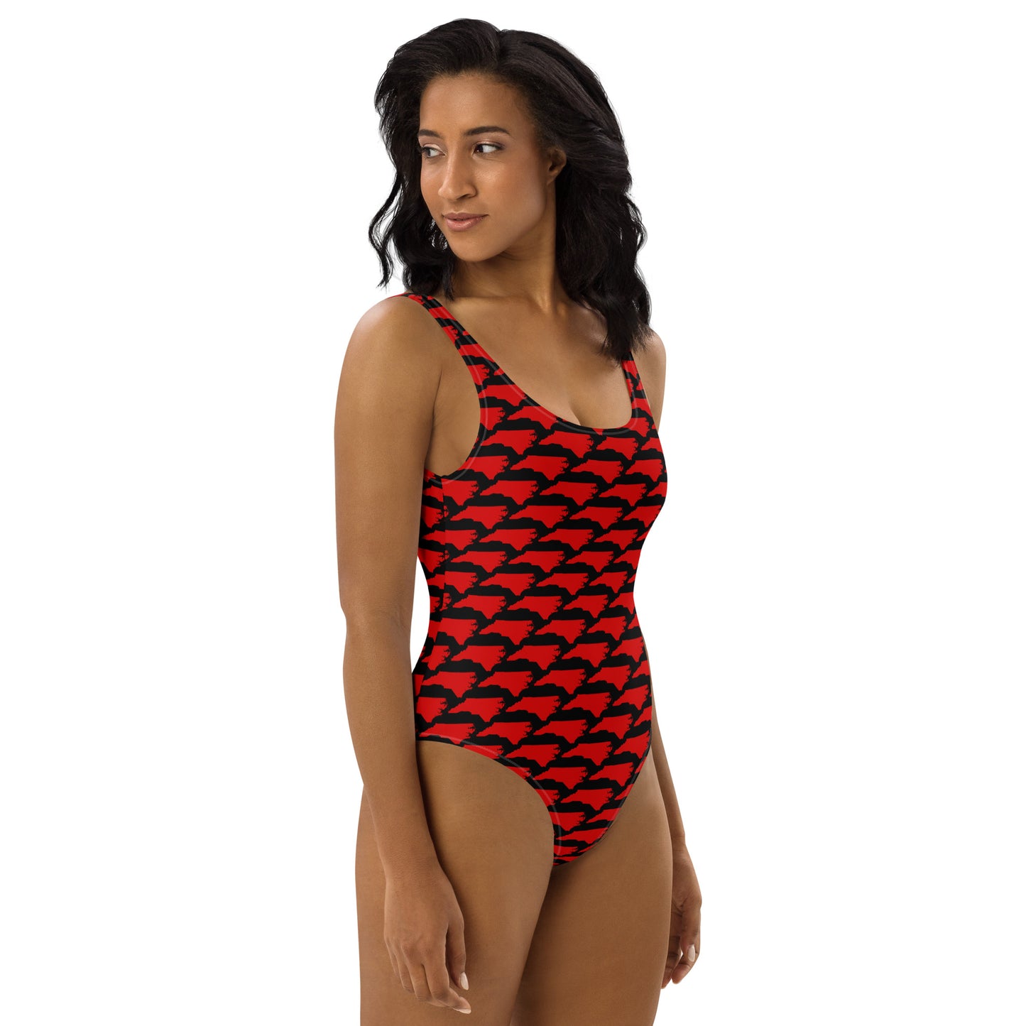 Woman with curly hair modeling Carolina Inferno Swimsuit, red NC pattern on black, front view