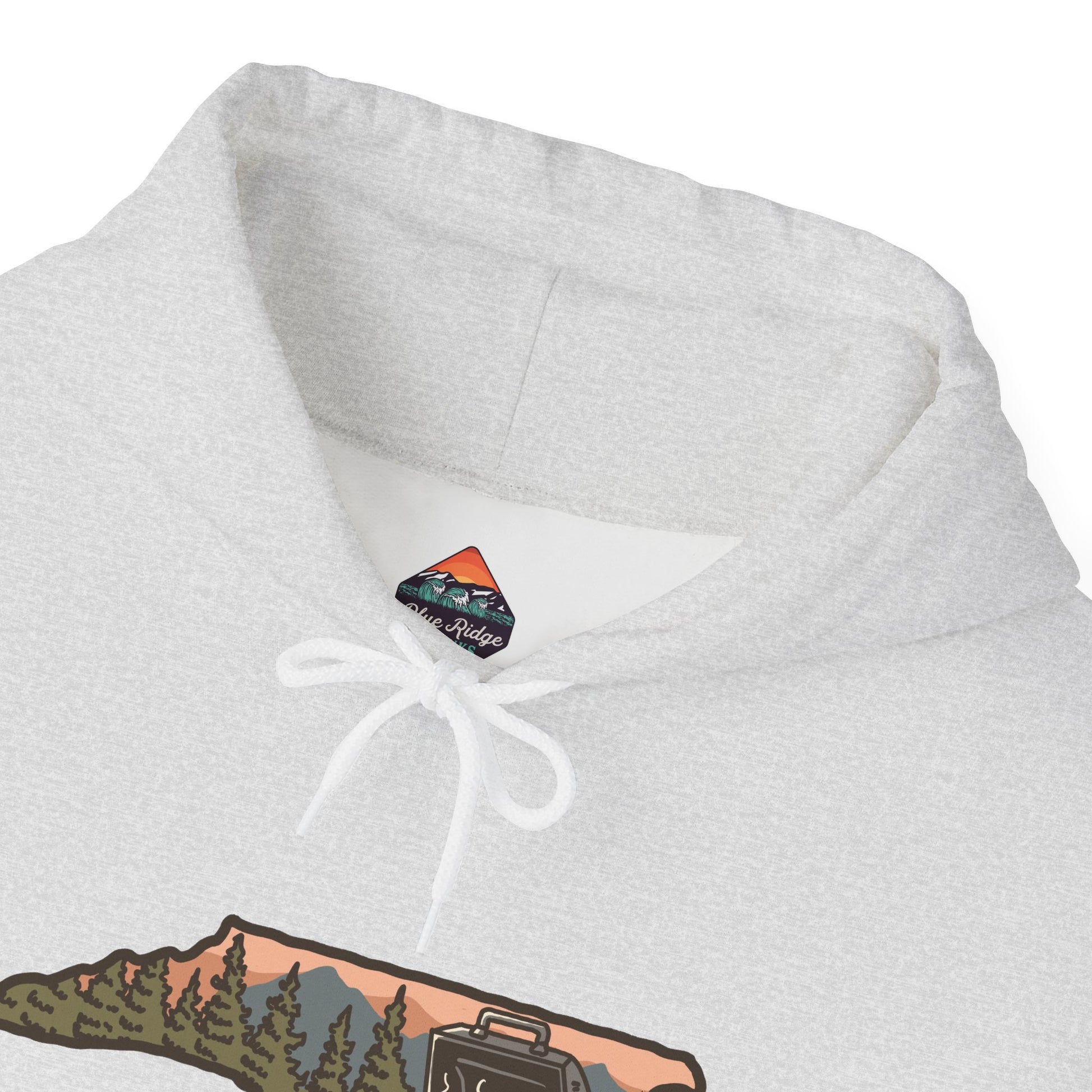 Close-up of chest graphic and hood details on ash gray NC BBQ Mountain Scene hoodie