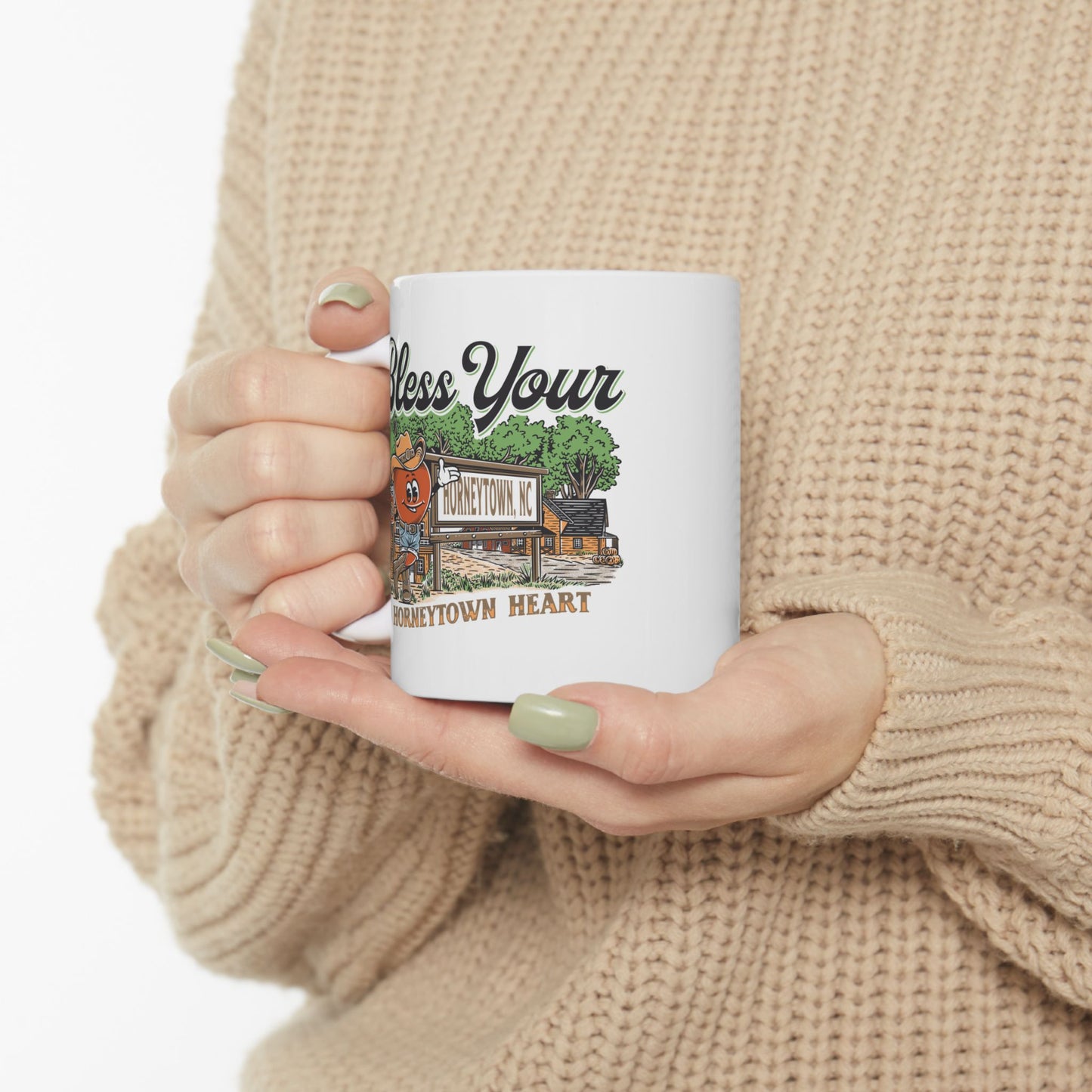 "White ceramic coffee mug featuring the playful 'Bless Your Horneytown Heart' slogan, inspired by the charming town of Horneytown, North Carolina. This 11oz mug showcases a whimsical design with nature-inspired elements, such as lush greenery and subtle floral accents, capturing the essence of North Carolina's picturesque landscapes. Perfect for coffee lovers who appreciate a touch of Southern charm and wit."