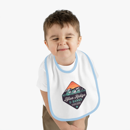 "Blue Ridge & Banks Logo – Baby Bib Shirt in White/Light Blue: Adorable baby bib shirt featuring the elegant Blue Ridge & Banks logo. This charming piece combines comfort and style, perfect for your little one. The soft white fabric is accented with light blue trim, evoking the serene beauty of North Carolina's majestic Blue Ridge Mountains. Ideal for nature-loving families, this bib shirt captures the essence of the great outdoors with its subtle, nature-inspired design elements."