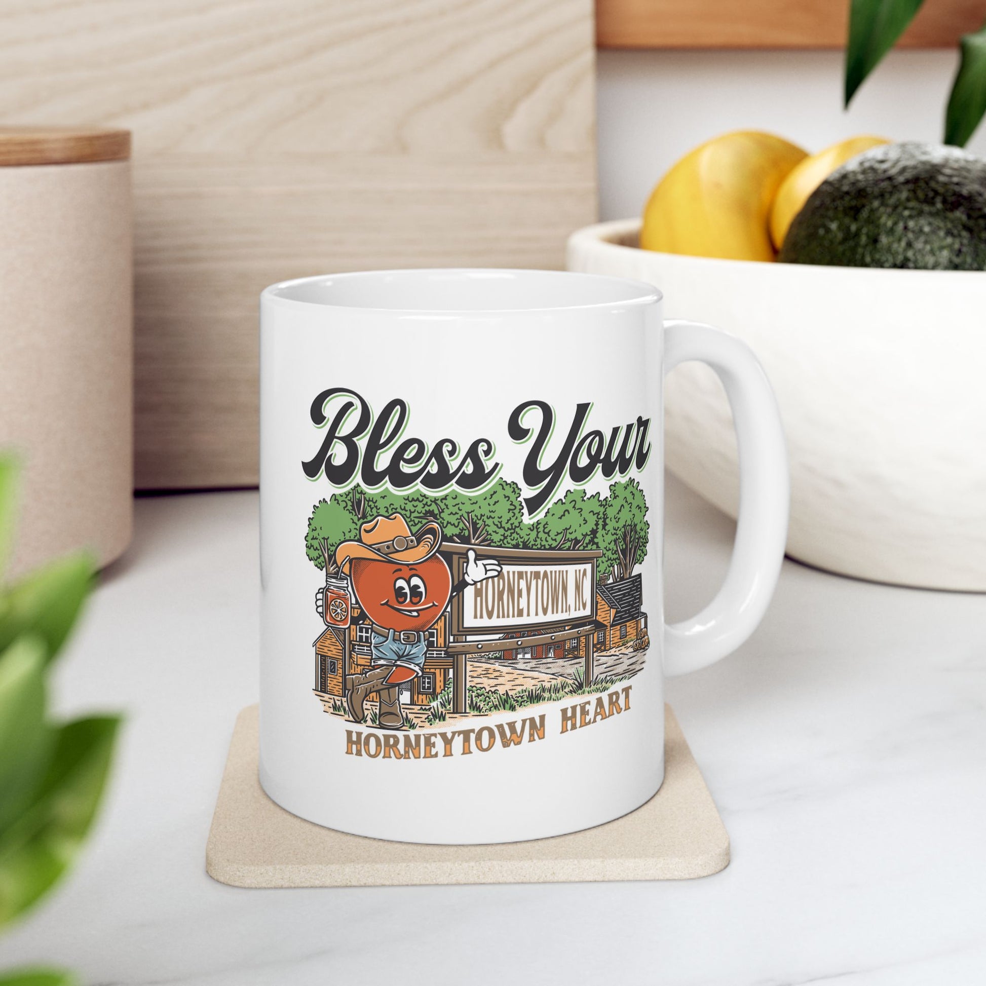"Bless Your Horneytown Heart – 11oz Ceramic Coffee Mug featuring a charming North Carolina-inspired design. This whimsical coffee mug showcases a playful nod to Horneytown, NC, with nature-inspired elements such as lush greenery and serene blue hues, perfect for adding a touch of Southern charm to your morning routine."