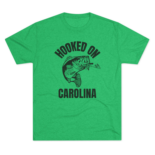 Green t-shirt with bold black text reading “Hooked on Carolina” and a graphic of a bass fish striking a lure.