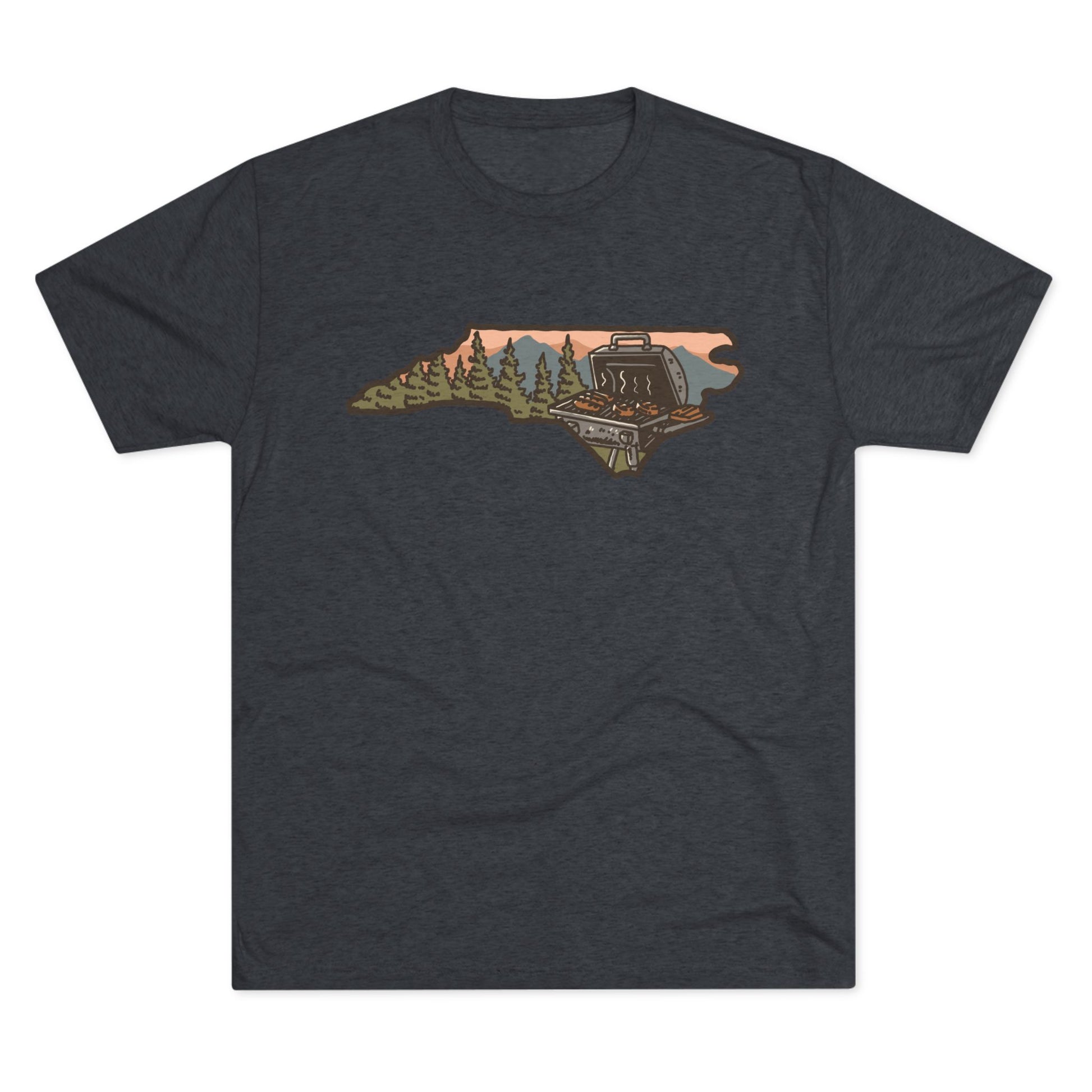 Navy T-shirt featuring a North Carolina state outline with a forest cabin, mountain backdrop, and backyard grill illustration.